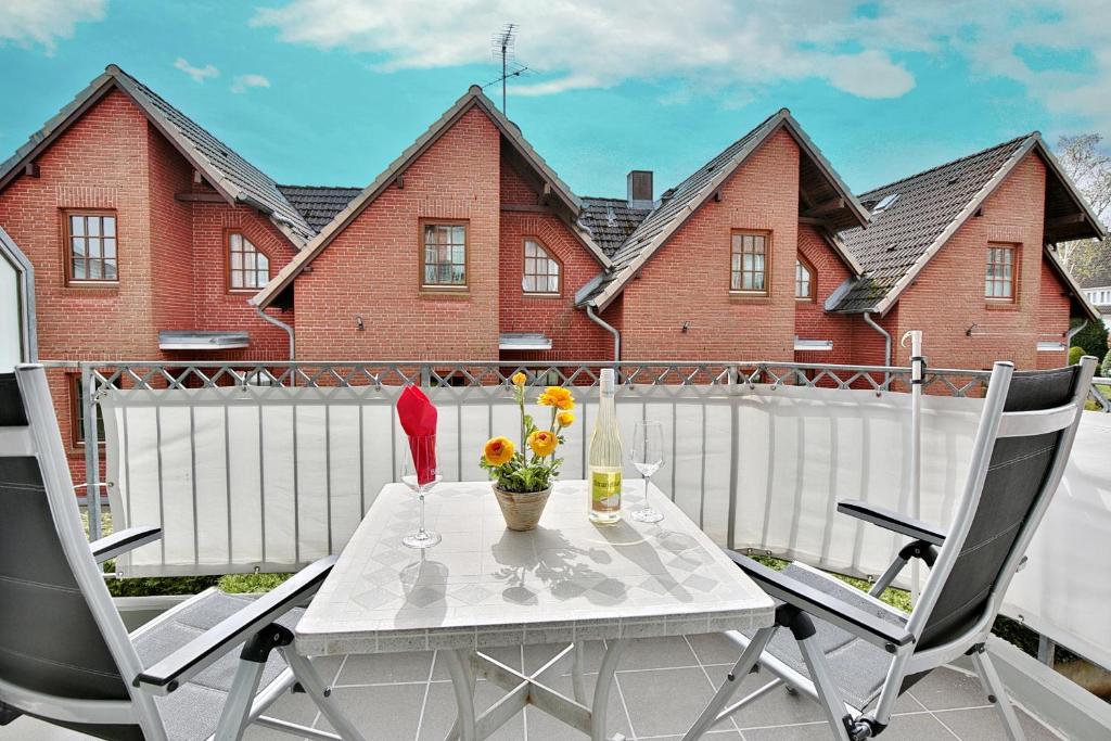 een tafel en 2 stoelen op een balkon met een wit hek bij Residenz Alte Bergstraße Residenz Alte Bergstrasse Appartement 9 in Scharbeutz