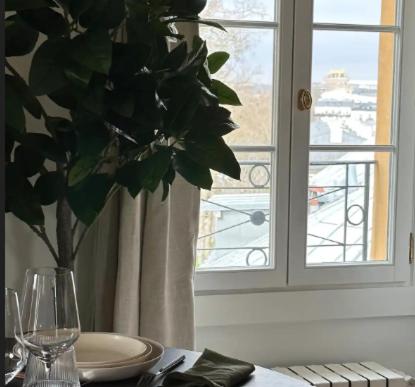 een tafel met een plaat en een vaas met een plant bij Amazing view on the Versailles Palace - Paris 15min in Versailles