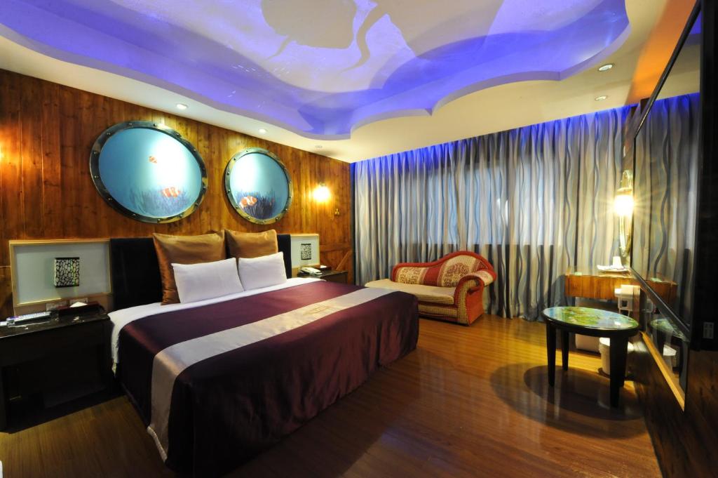 een hotelkamer met een groot bed en een bank bij ZJ Motel in Hsinchu City