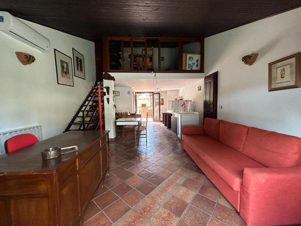 ein Wohnzimmer mit einem roten Sofa und einer Küche in der Unterkunft HARMONY HOUSE APARTMENT in Syrakus