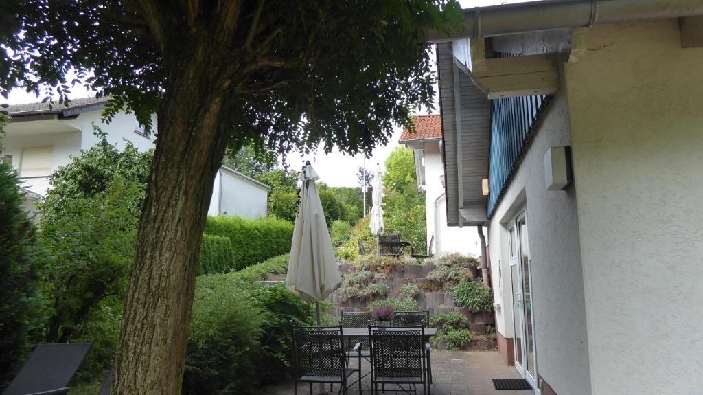 eine Terrasse mit einem Tisch, einem Sonnenschirm und einem Baum in der Unterkunft Landleben - Ferienhaus 2 in Fritzlar