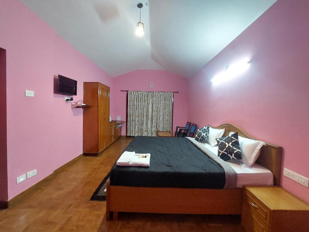 a bedroom with a large bed with pink walls at TRIOS in Ooty