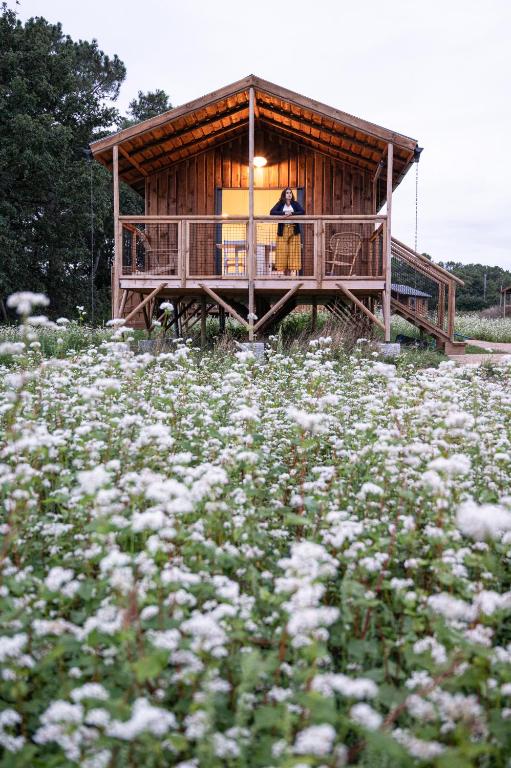 a woman standing on the porch of a house with a field of flowers at Dihan Evasion in Ploemel