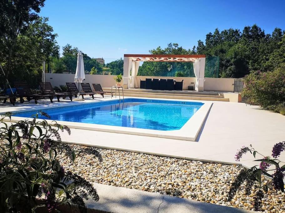 a swimming pool in a backyard with a pergola at Villa La Plazza in Dugopolje