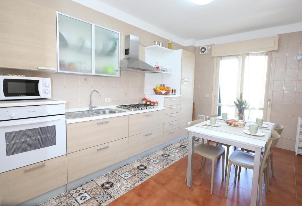 a kitchen with white appliances and a table with chairs at Casa in centro Ragusa con parcheggio privato in Ragusa