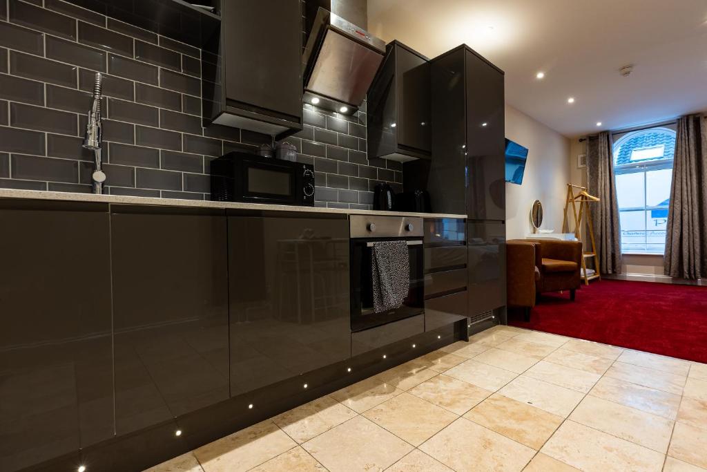 a kitchen with black appliances and a living room at Lovely 1 Bed Apartment in City Centre in Norwich