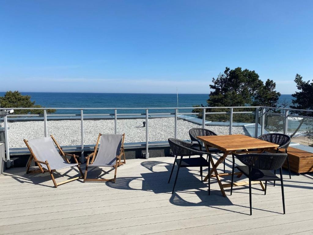 une terrasse en bois avec une table et des chaises, ainsi que la plage dans l'établissement Appartement in Gski mit Terrasse, à Gąski