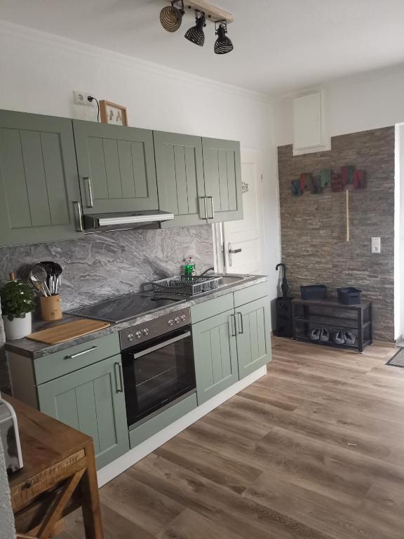 a kitchen with green cabinets and a stove top oven at Pauls Hexenhaus Wohnung Hexe mit Fahrrad Garage und Innenhof für Motorräder in Thale