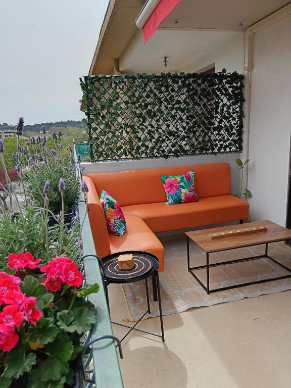 un canapé orange assis sur un patio avec des fleurs dans l'établissement Cosy T3, proche centre ville, à Aix-en-Provence