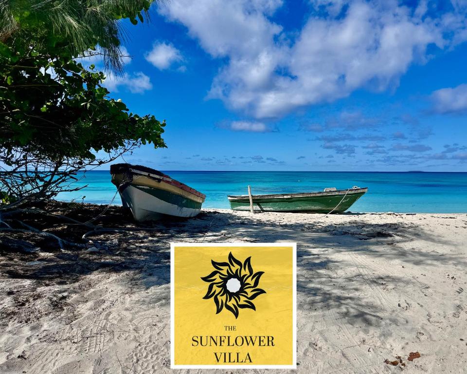 un panneau sur une plage avec deux bateaux sur le sable dans l'établissement The Sunflower Villa, à Grand Turk