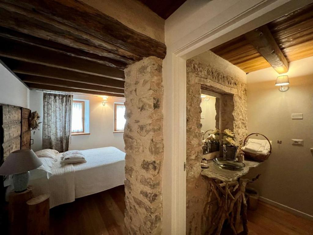 een slaapkamer met een bed en een stenen muur bij B&B Il Gufo in Erto