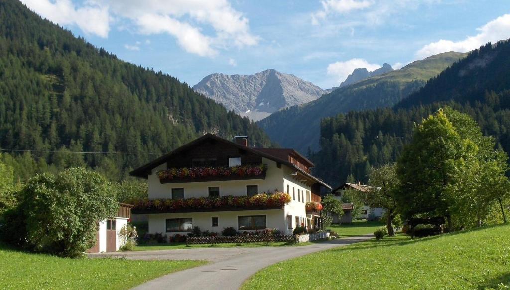 uma casa num campo com montanhas ao fundo em Ferienwohnung Lechtal mit 2 Schlafzimmer und großem Balkon em Bach