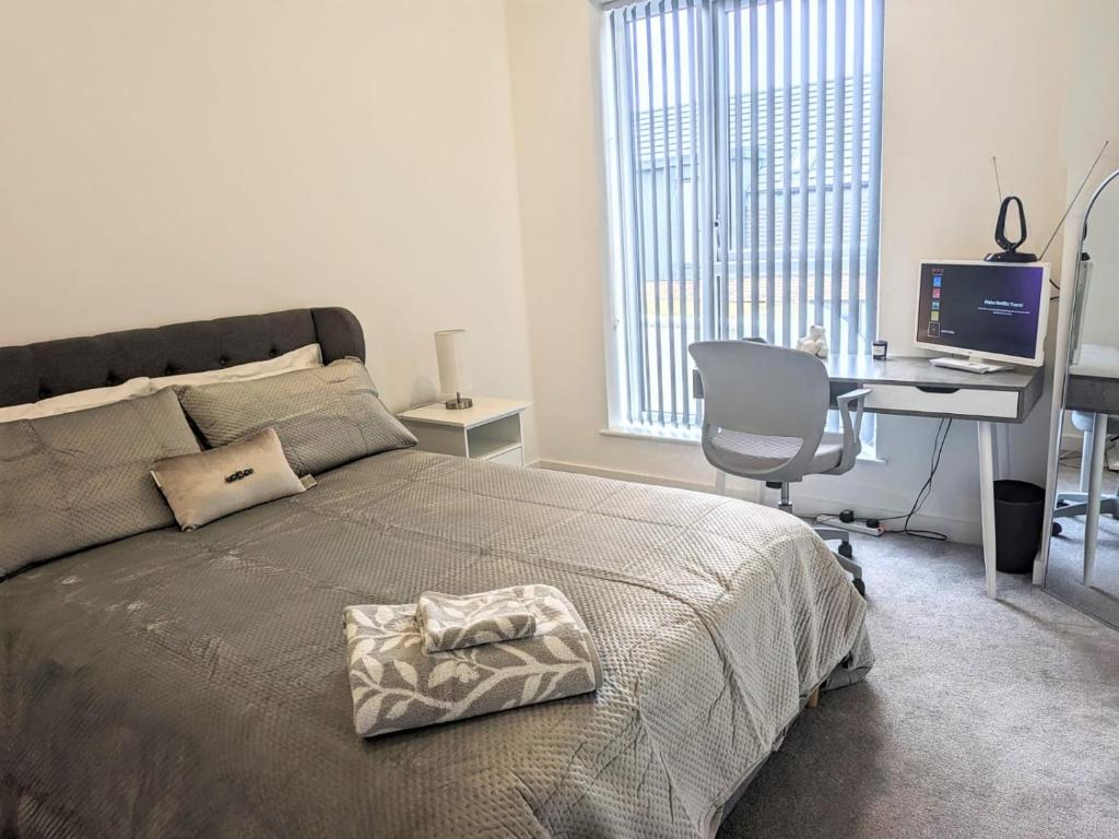 Schlafzimmer mit einem Bett und einem Schreibtisch mit einem Computer in der Unterkunft Contemporary Double Ensuite Room in Birmingham