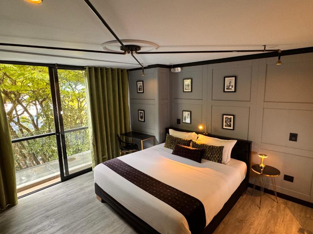 Un dormitorio con una cama grande y una ventana grande. en Hotel Helene, en Medellín
