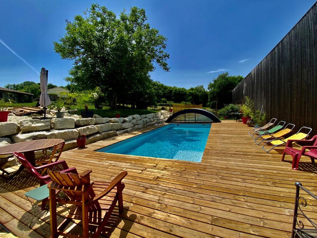 une terrasse en bois avec des chaises et une piscine dans l'établissement La Salamandre Enchantée, à Louzac - Saint-André
