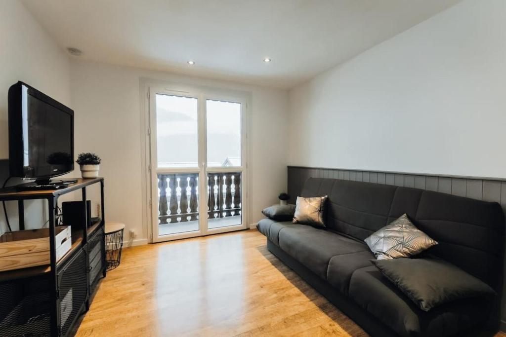 uma sala de estar com um sofá preto e uma televisão em Punta Helbronner Furnished studio em Saint-Gervais-les-Bains