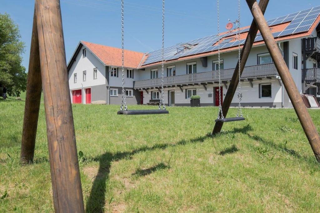 une aire de jeux vide avec balançoires devant un bâtiment dans l'établissement Gesamtes Ferienhaus in Buchenberg mit Grill, Garten und Terrasse, à Buchenberg