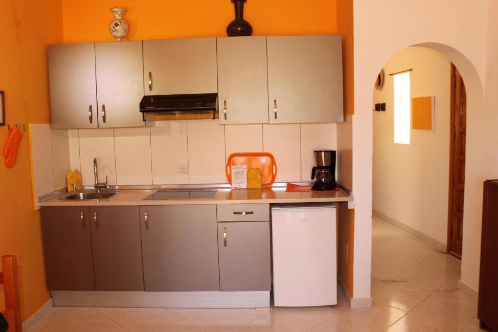 a kitchen with gray cabinets and an orange wall at Liebevoll eingerichtet, ruhiges Ferienapartment mit separatem Schlafzimmer in La Pared