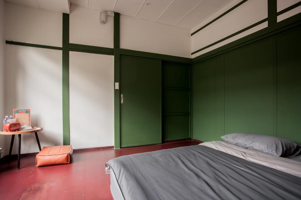 a bedroom with green walls and a bed and a table at Xinghua Room in Kaohsiung