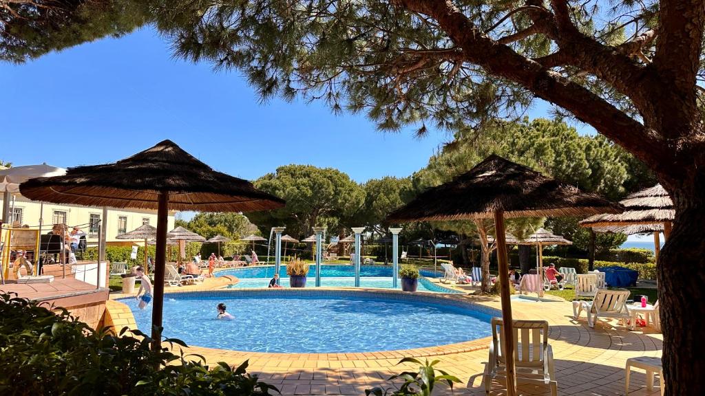 a swimming pool with umbrellas and people in a resort at Bicos 303 - Shared Pool - 6 Guests - Albufeira in Albufeira