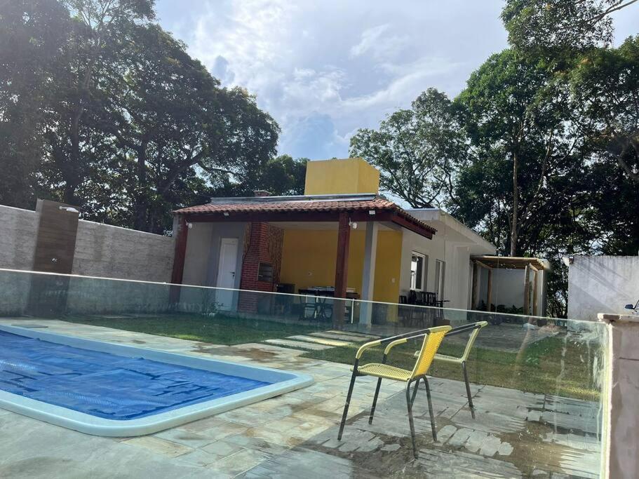 einen Stuhl neben einem Pool neben einem Haus in der Unterkunft Casa com piscina Embu-Guaçu/ Itapecerica (Chácara) in Embu-Guaçu