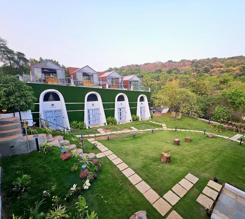 a large green building with white doors and a yard at NYAST VALLEY RESORT, ARPORA in Arpora
