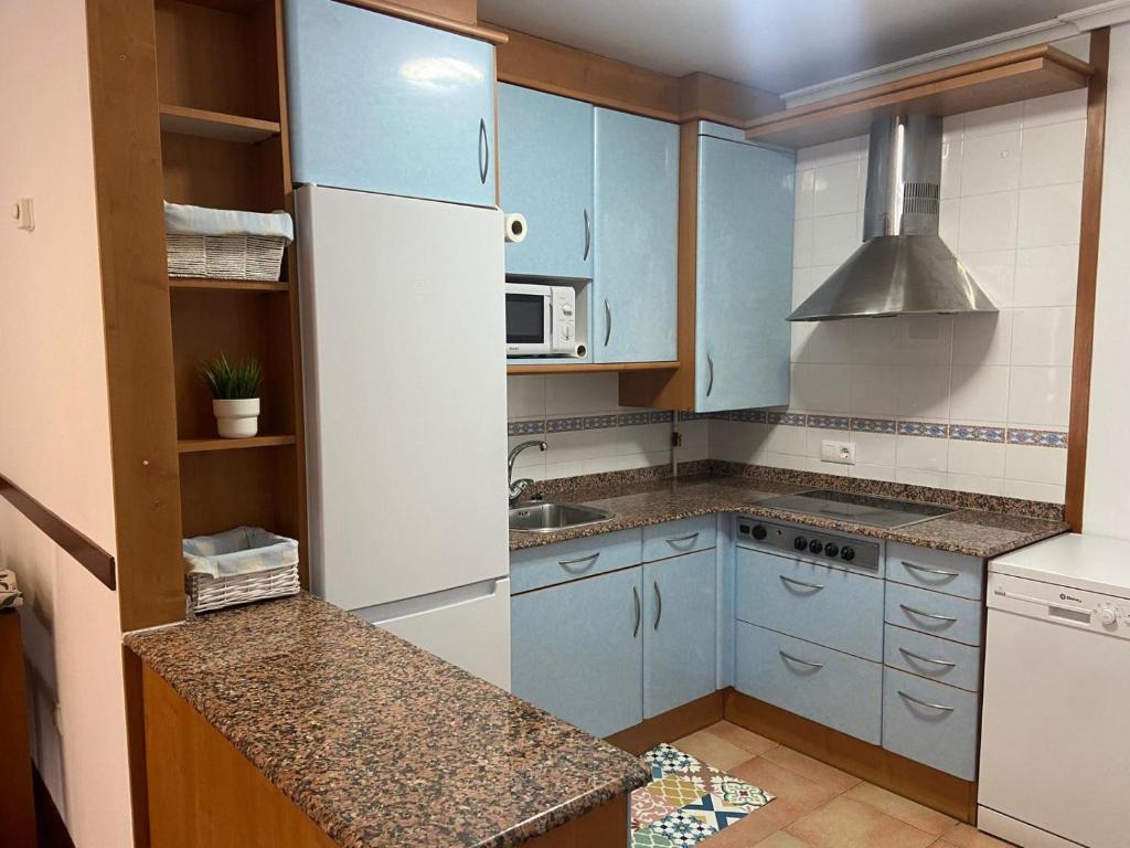 La cuisine est équipée de placards bleus et d'un réfrigérateur blanc. dans l'établissement Vivienda vacacional: Los Abuelos, à San Vicente de la Barquera