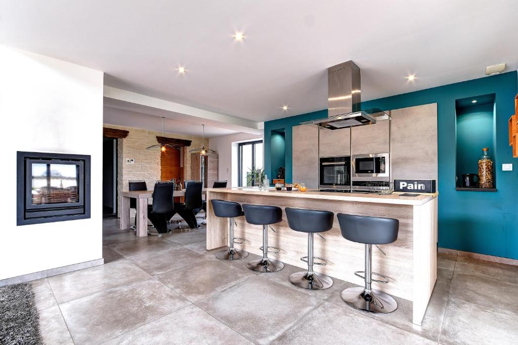 a kitchen with blue walls and a bar with stools at Ici on est à Laiz in Laiz