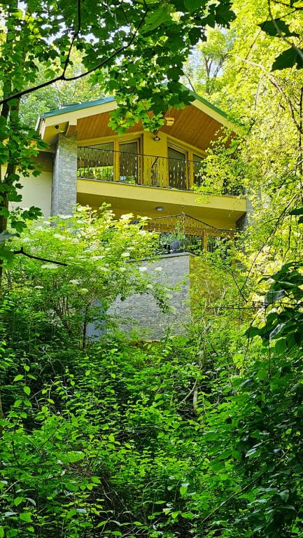 ein gelbes Haus mit Balkon in einem Wald in der Unterkunft Chalet Robinson in Modra