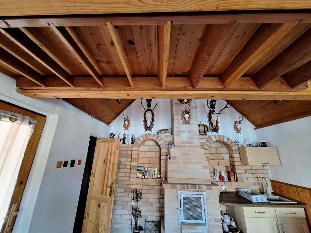 a kitchen with wooden ceilings and a brick fireplace at Chata u poľovníka 