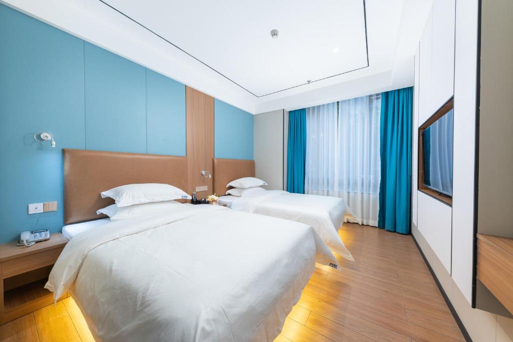 Duas camas num quarto com paredes azuis em Guangzhou Haiyue Hotel em Guangzhou