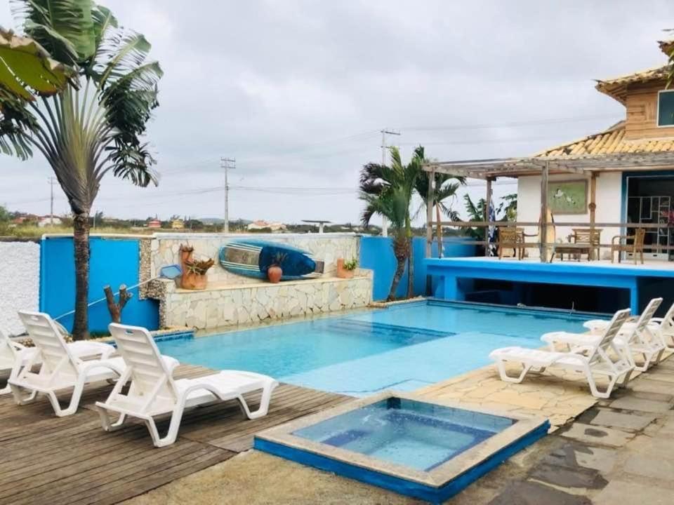 uma piscina com cadeiras brancas e uma casa em Casa Marina VIP em Búzios