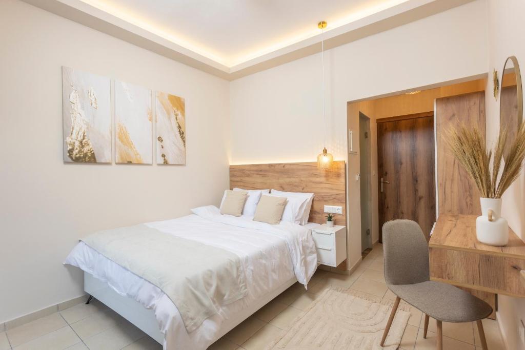 a white bedroom with a large bed and a desk at Dimitra Central Apartments Chanioti in Hanioti