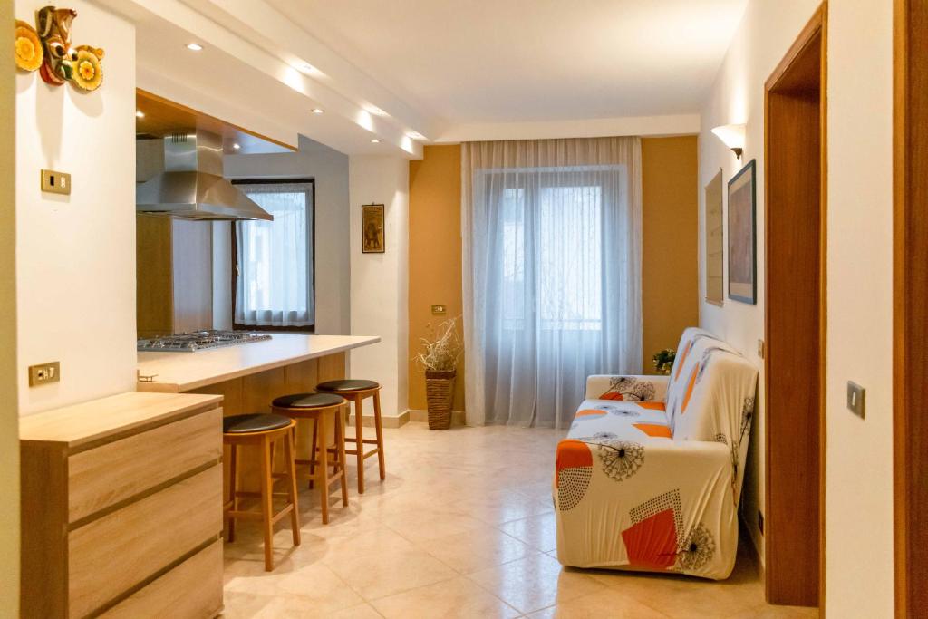 uma cozinha e sala de estar com um balcão e cadeiras em Appartamento Spazioso a 30min da Cortina em Domegge di Cadore