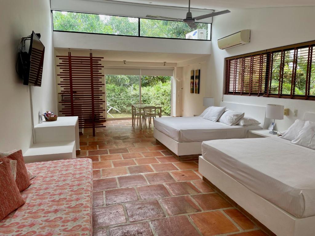 a bedroom with two beds and a living room at La Masia Hotel Boutique in Anapoima