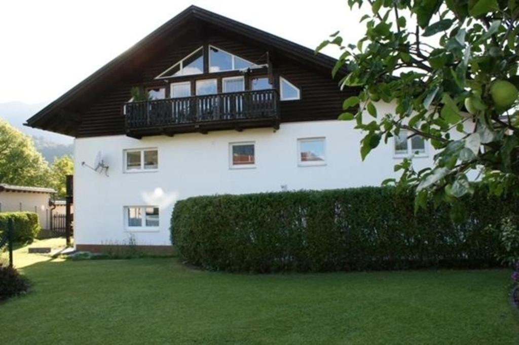 a white house with a balcony and a yard at Gemütliche Ferienwohnung in Pflach mit Garten in Pflach
