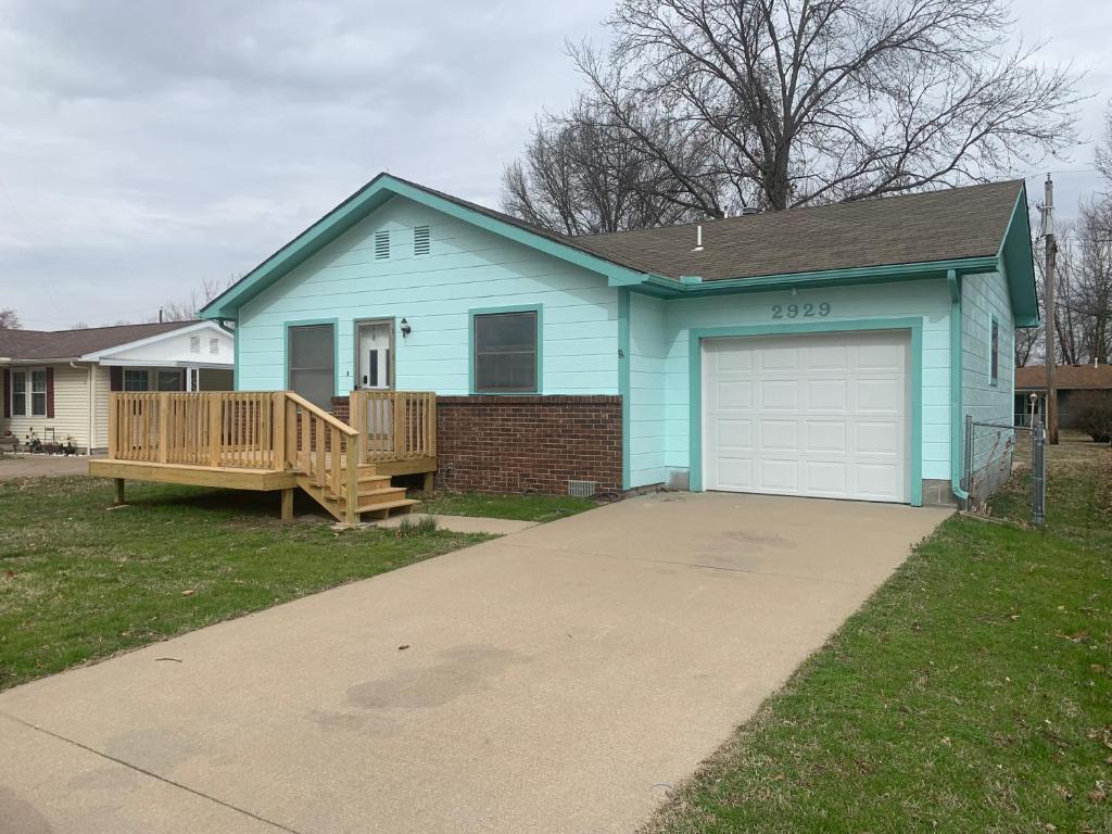 a blue house with a porch and a garage at Whiteshomesplus in Joplin