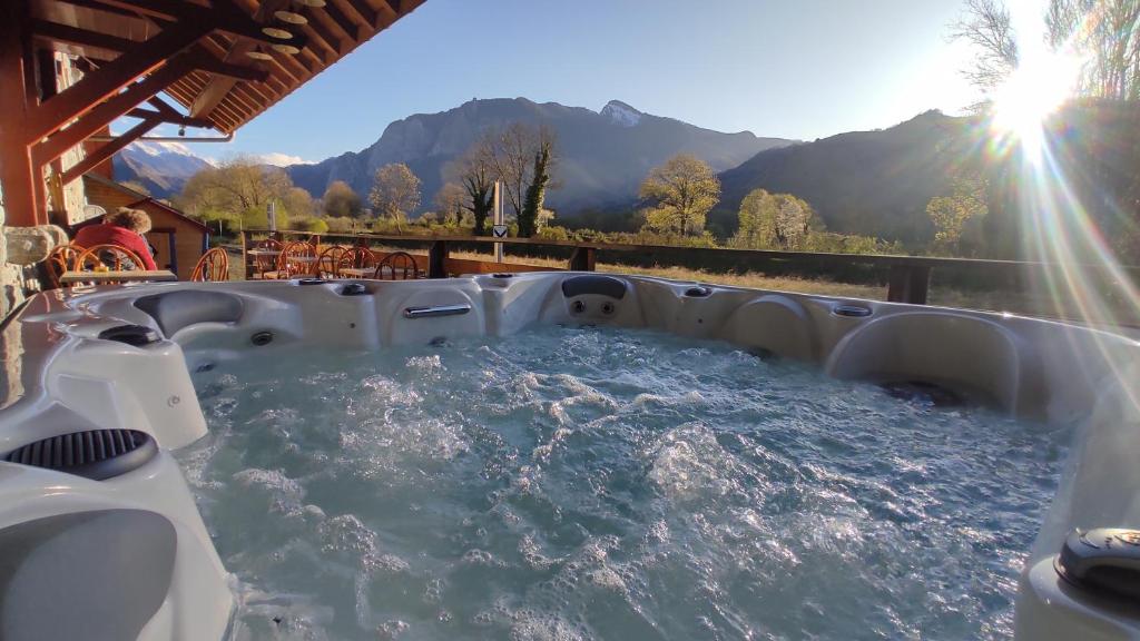 a hot tub on a patio with mountains in the background at Hôtel spa Transhumance & cie in Bedous