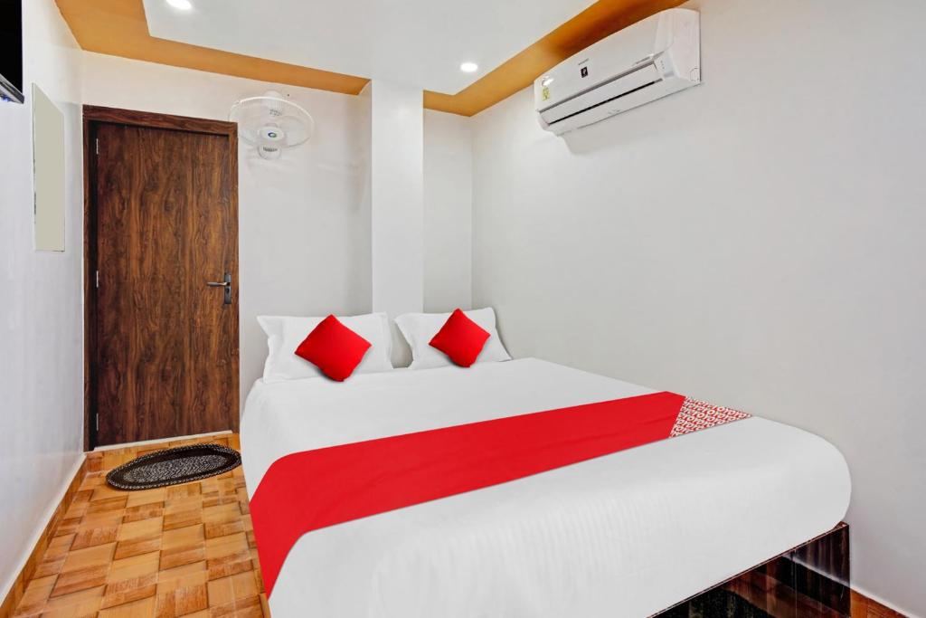 a bedroom with a white bed with red pillows at Super OYO Flagship 81158 Hotel Aditya Inn in Patna