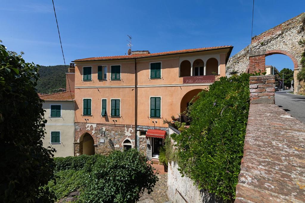 um grande edifício de tijolos com janelas verdes numa rua em Villa Salvarezza em Noli