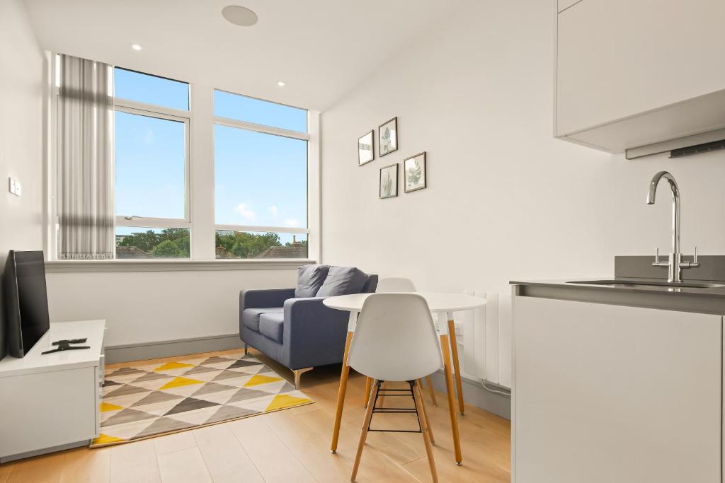 cocina y sala de estar con mesa y silla en One Bedroom Serviced Apartments in Harrow, en Pinner