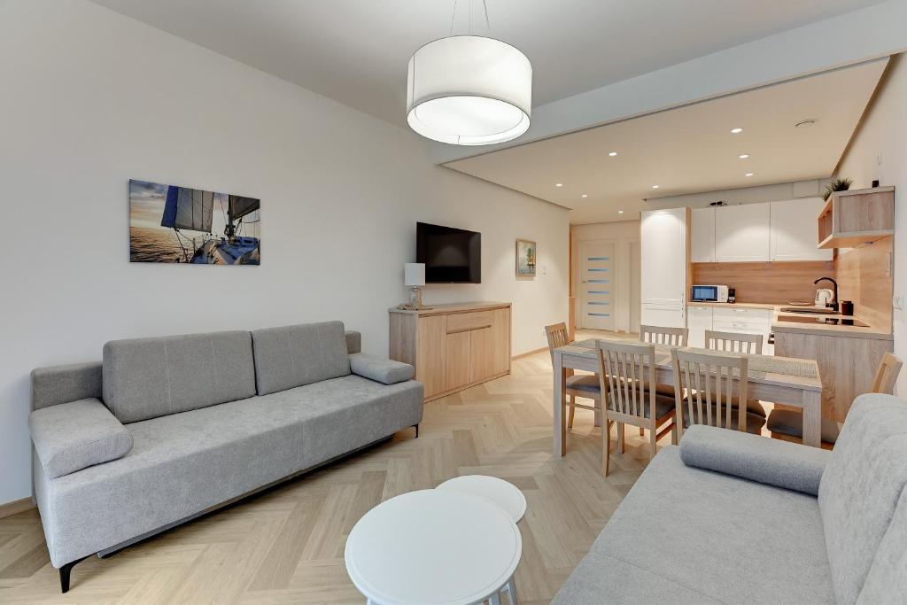ein Wohnzimmer mit einem Sofa und einem Tisch in der Unterkunft Comfy Apartments - Rodzinny Nadmorski Dwór I 10 minut plaża in Danzig