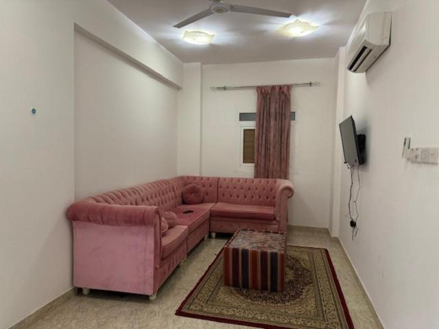 a living room with a pink couch and a tv at Mabeela Lux Apartment in Seeb