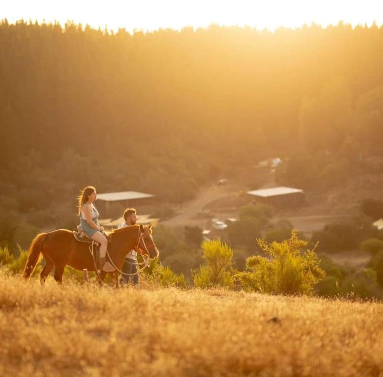 un hombre y una mujer montando un caballo en un campo en Glamping, escapada en la naturaleza, en San Clemente
