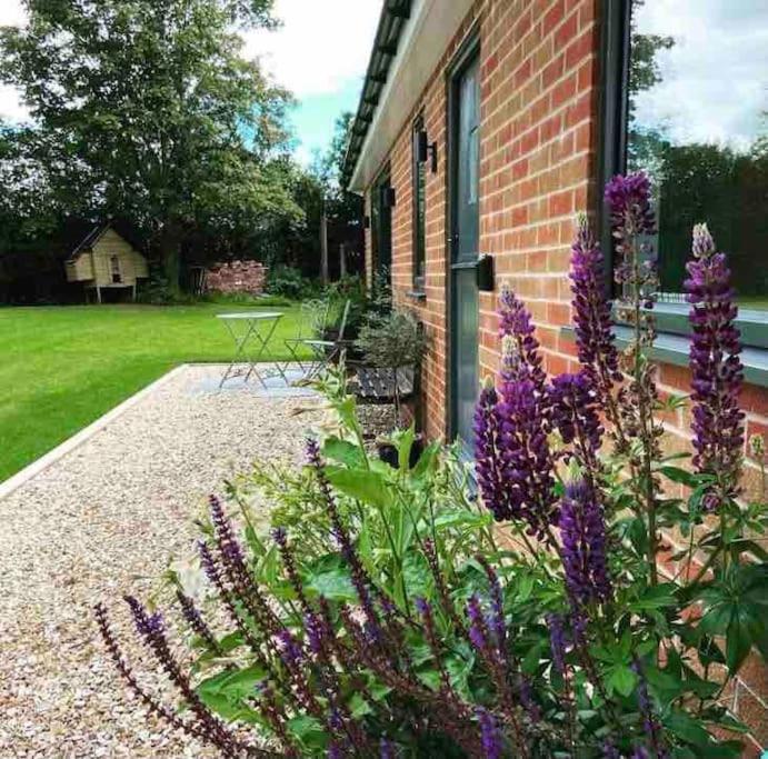 a garden with purple flowers in front of a house at Garden Room Dormston in Kington
