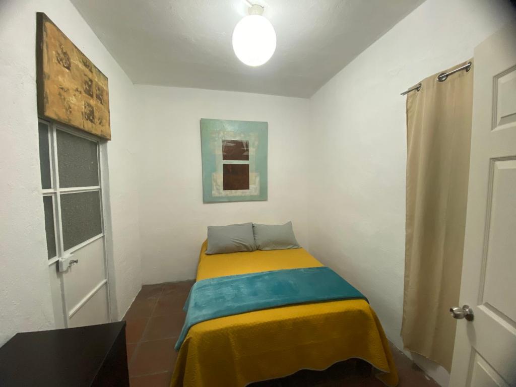 a small bedroom with a bed with a yellow and blue blanket at Depa Santa María in Malinalco