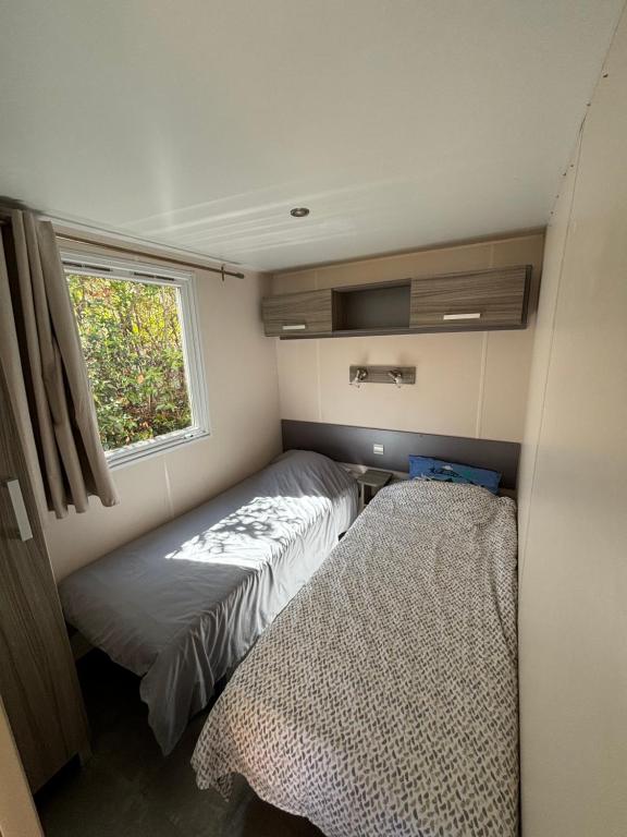 a small bedroom with a bed and a window at Mobilhome in Névian