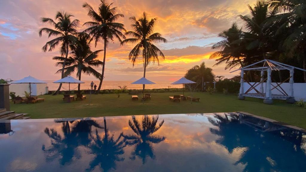 a reflection of a sunset in a pool with palm trees at Sea Star Boutique Hotel in Hikkaduwa