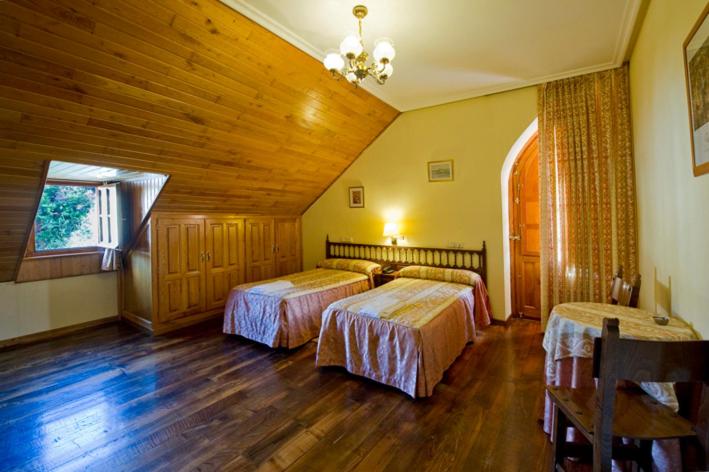 a bedroom with two beds and a wooden ceiling at Hotel Restaurante La Casilla in Cangas del Narcea