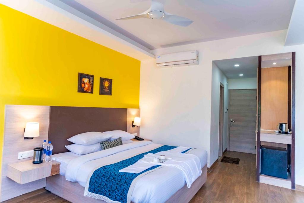 Hotel Bob's N Barley في دارامشالا: غرفة نوم بسرير كبير وبجدار اصفر